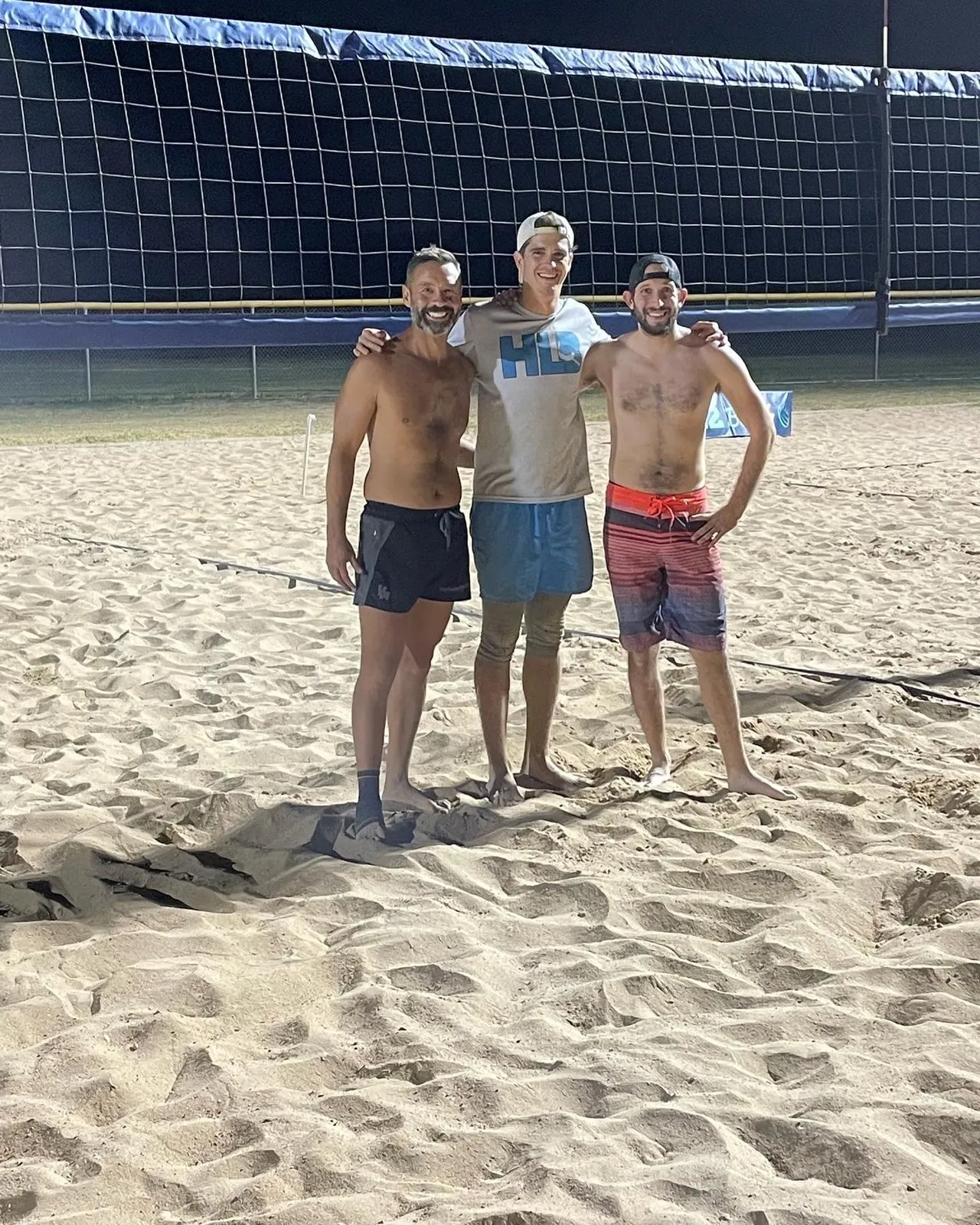 Three players on the sand at night after the blind draw win